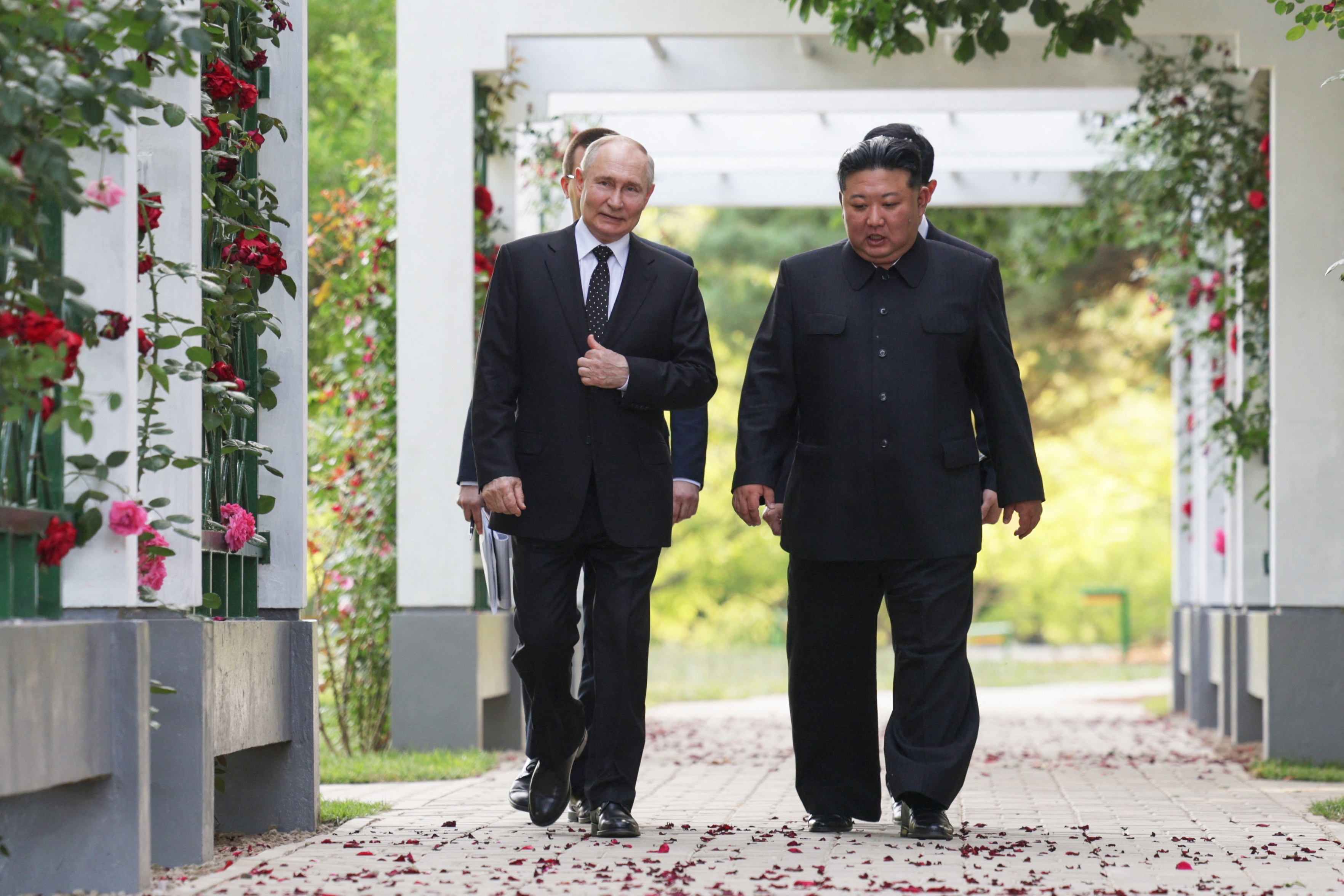 In this pool photograph distributed by the Russian state agency Sputnik, Russian President Vladimir Putin (L) and North Korea's leader Kim Jong Un (R) walk before a wreath-laying ceremony at the Liberation Monument in Pyongyang, on June 19