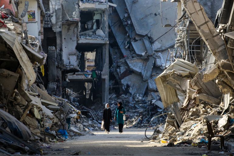 Palestinian women make their way past destroyed buildings in Khan Yunis on June 20