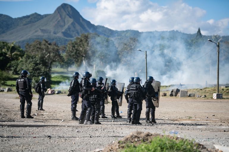 French gendarmes stand amid tear gas as pro-independence protesters clash with them during an operation to remove a roadblock on Paul-Emile Victor avenue in Dumbea on the French Pacific territory of New Caledonia