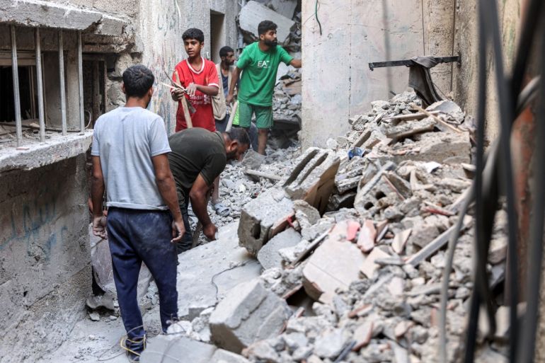 Men search through the rubble of the house of the sister of Ismail Haniyeh, the Doha-based political bureau chief of the Palestinian Islamist movement Hamas, after it was hit by Israeli bombardment in the Shati camp for Palestinian refugees west of Gaza City on June 25, 2024