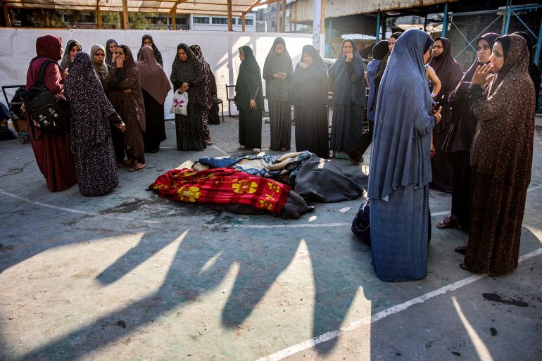 Women gather by the retrieved bodies of victims killed in the aftermath of overnight Israeli bombardment at the Asma school run by the UN Relief and Works Agency for Palestine Refugees (UNRWA), in the Shati camp for Palestinian refugees west of Gaza City