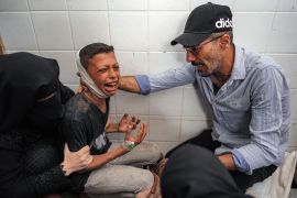 A woman and a man comfort an injured boy mourning the loss of his father who was killed by an Israeli bombardment of the Maghazi refugee camp in the central Gaza Strip, on June 25, 2024 [Bashar Taleb/AFP]