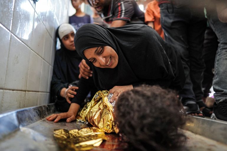 A woman bids farewell to her child, who was killed in an overnight Israeli bombardment in al-Maghazi in the central Gaza Strip