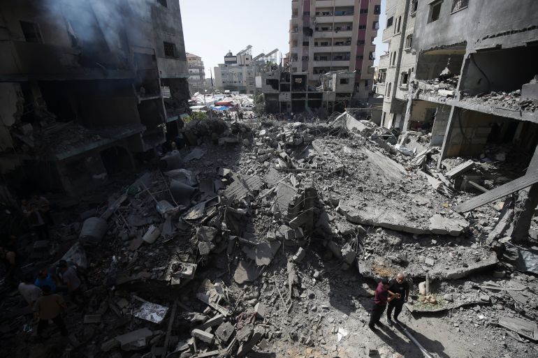 Palestinians look at the aftermath of the Israeli bombing in Nuseirat refugee camp, Gaza Strip, Saturday, June 8