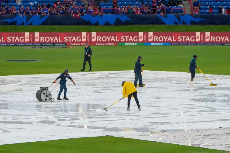 Groundsmen sweep water from the covers as rain delays the start of the men's T20 World Cup cricket match between Sri Lanka and Nepal at Central Broward Regional Park Stadium, Lauderhill, Florida, Tuesday, June 11, 2024. (AP Photo/Lynne Sladky)