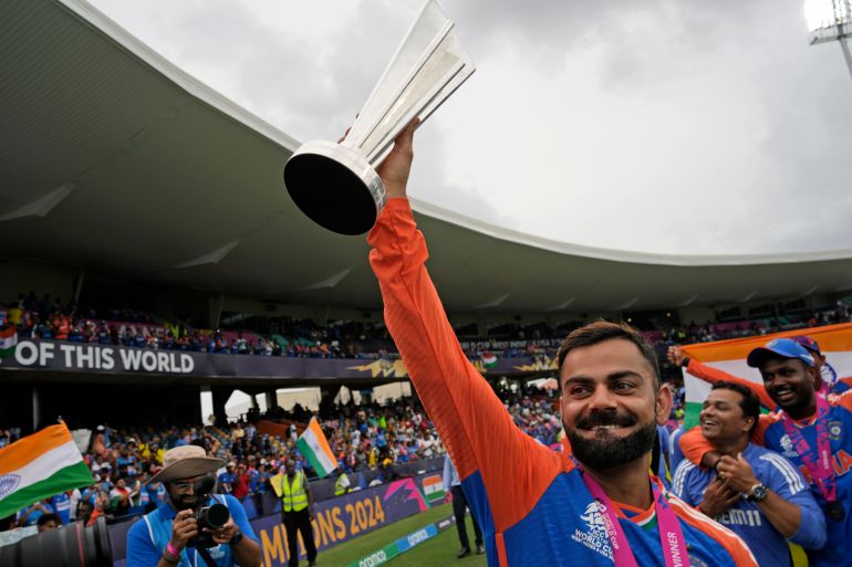 India's Virat Kohli carries the winners' trophy as he celebrates after India won the ICC Men's T20 World Cup final cricket match against South Africa at Kensington Oval in Bridgetown, Barbados, Saturday, June 29, 2024. (AP Photo/Ramon Espinosa)