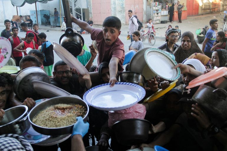 Palestinian children gather to receive food cooked by a charity kitchen, amid food scarcity, as Israel-Hamas conflict continues, in the northern Gaza Strip, July 18, 2024. REUTERS/Mahmoud Issa