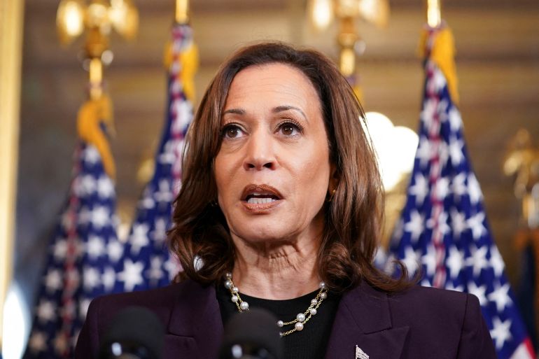 Kamala Harris in a brown suit with American flags behind her