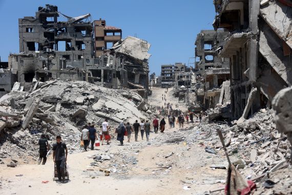 Palestinians make their way over the dirty of rubble, past destroyed buildings after the Israeli military withdrew following a two-week offensive from the Shujaiya neighbourhood