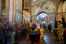 Servicemen hold the decorations of Ukraine activist and serviceman Mykola Kokhanovsky, who was killed in battle near Kharkiv, as mourners lay flowers on his coffin during his funeral ceremony in St Michael&#039;s Golden-Domed Monastery in Kyiv on July 16, 2024 [Sergei Supinsky/AFP]