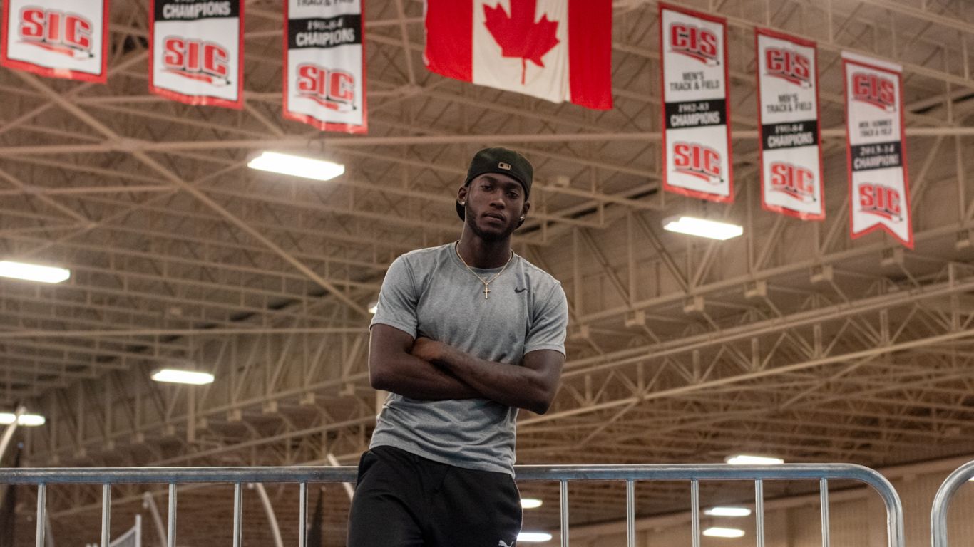 Tamarri Lindo poses under the Canadian flag in an indoor sports arena.