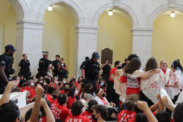 Police officer approaches a ring of protesters in red