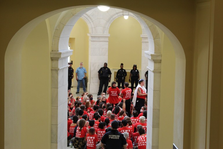 Seen between the archways of the Cannon Building, protesters gather in a sea of red T-shirts, bearing the slogan, "Not in our name: Jews say stop to arming Israel."