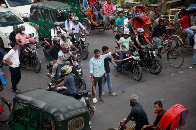 People in their early 20s direct traffic at a main intersection in Dhaka