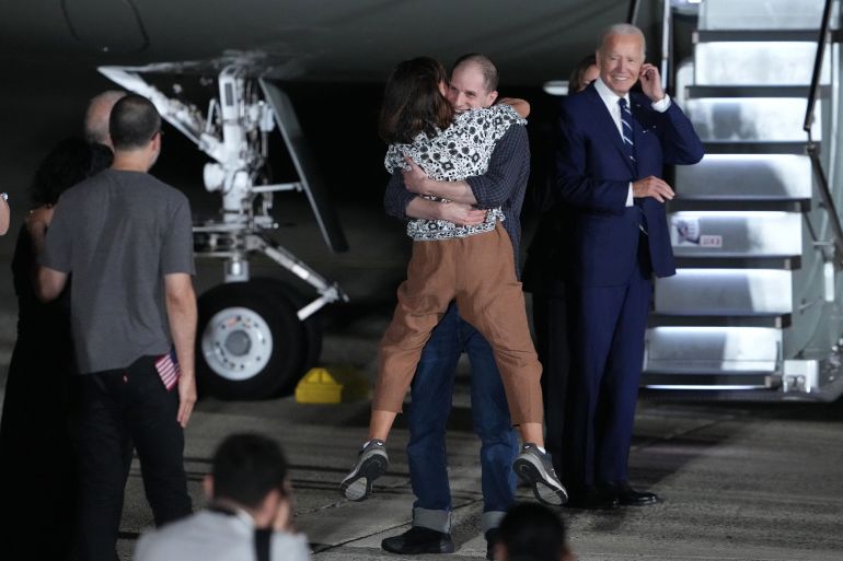 Evan Gershkovich hugging his mum after landing back in the US. They are standing at the bottom of the plane's steps. He has lifted his mum off the ground.