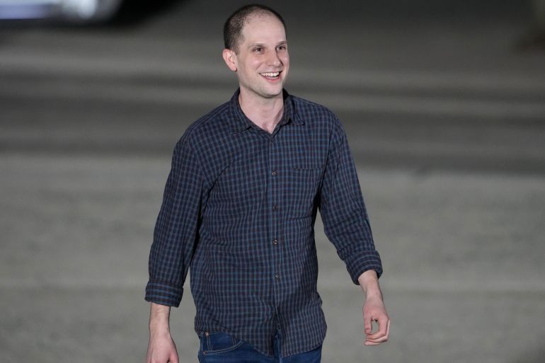 Evan Gershkovich walking on the tarmac at the airport. He looks thin, but very happy.