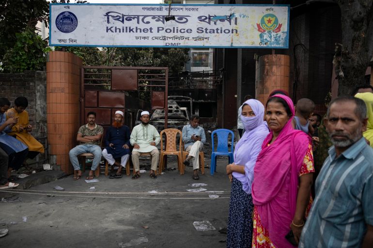 People keep guard in front of a police station which was vandalised on Monday, in Dhaka