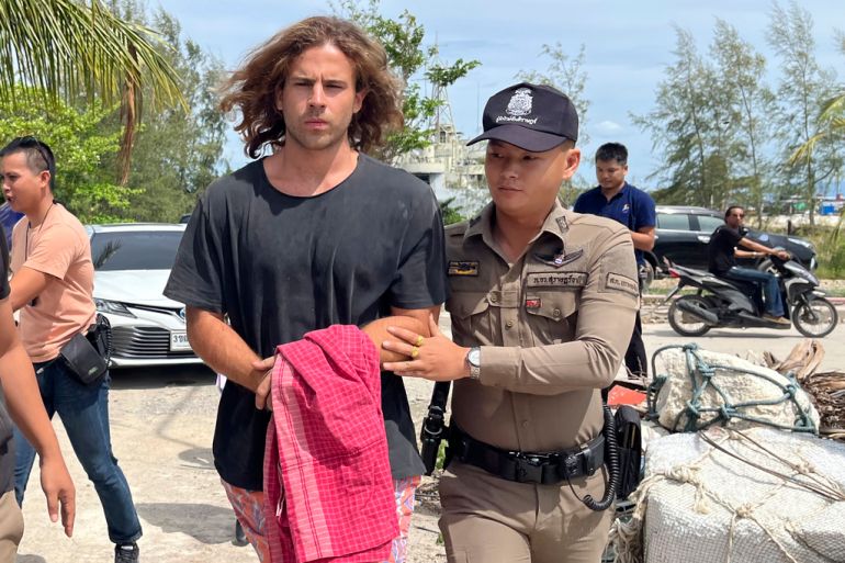 A Thai police officer escorts Daniel Sancho Bronchalo