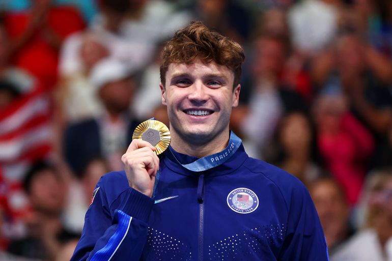 Swimmer holding gold medal.