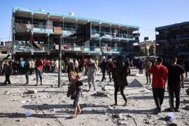 Palestinians walk in the courtyard of the al-Jaouni school after an Israeli strike. [Eyad Baba/AFP]