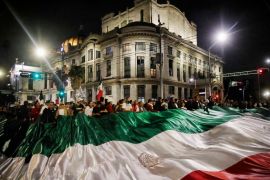 Judiciary workers and students hold a giant flag as they block streets near the former headquarters of the Senate of Mexico, known as Casona de Xicotencatl, during a protest in Mexico City. [Rodrigo Oropeza/AFP]