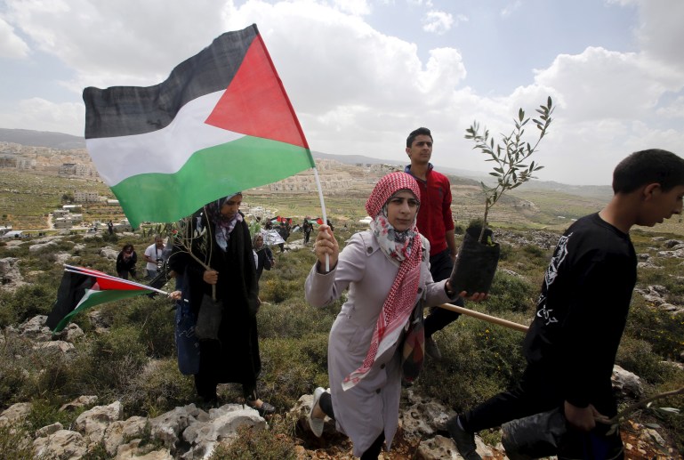 A Palestinian protester holds a Palestinian flag and an olive tree during a demonstration marking Land Day and against Jewish settlements in Wadi Foukeen near the West Bank city of Bethlehem March 30, 2015. Palestinians mark Land Day on March 30, the annual commemoration of protests in 1976 against Israel's appropriation of Arab-owned land in the Galilee. REUTERSMussa Qawasma