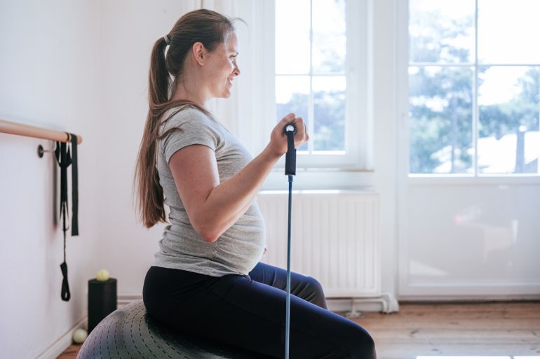 Pregnant woman doing sport using resistance elastic bands. غيتي