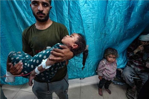 رجل يحمل طفلة أصيبت في غارات إسرائيلية على البريج في دير البلح بوسط قطاع غزة