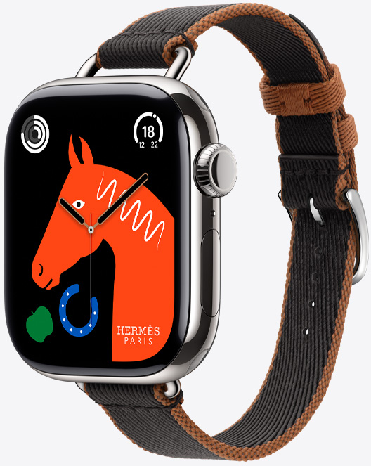 Angled view of the new Twill Jump Attelage Single Tour band in Noir/Gold (black with gold trim) with the ‘Lucky Horse’ watch face featuring an orange horseʼs head, a green apple and a blue horseshoe.