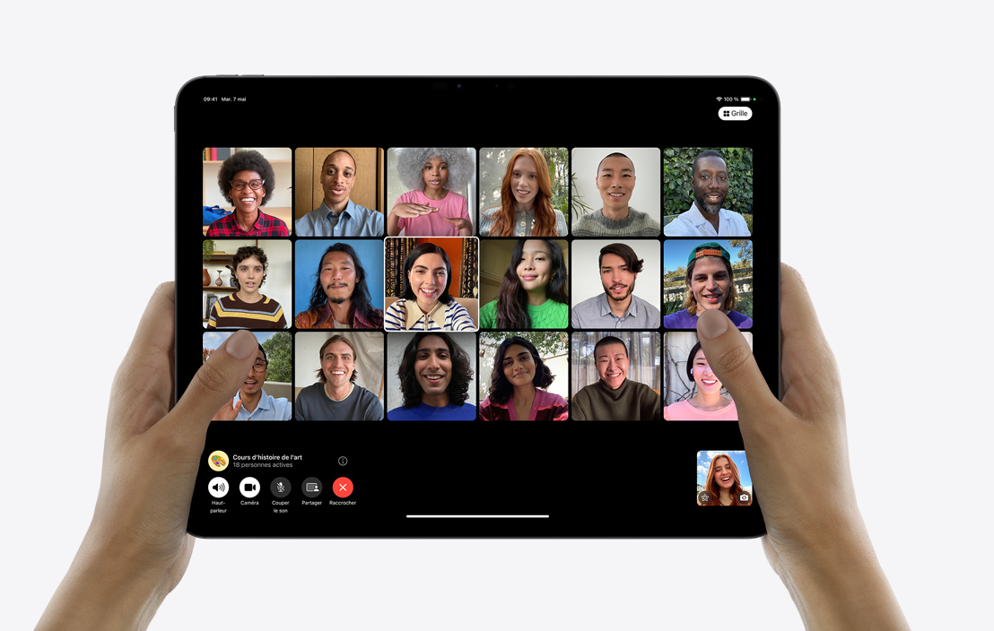 Deux mains tenant un iPad Pro qui affiche un appel FaceTime de groupe.