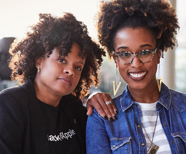 Foto de duas mulheres, uma confiante e a outra sorrindo, olhando para a câmera.