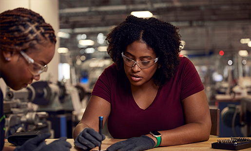 Camara and a colleague each wear protective goggles as they work together at a lab station.