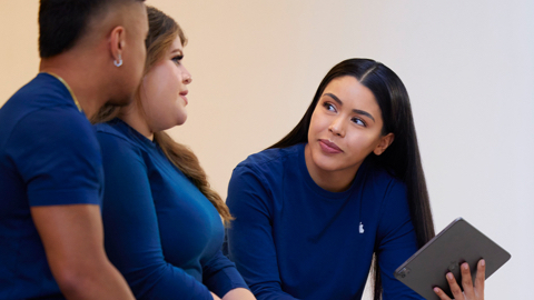 Tres empleados de Apple Retail hablan entre ellos, una sostiene un iPad.