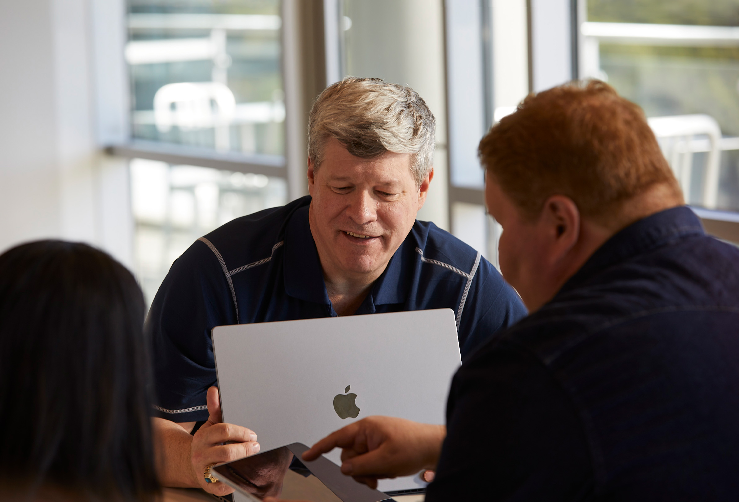 Tre Apple-ansatte bruker MacBook og iPad til å samarbeide.