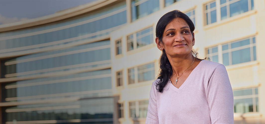 Ramani, assise devant un immeuble de bureaux, regarde vers le côté.