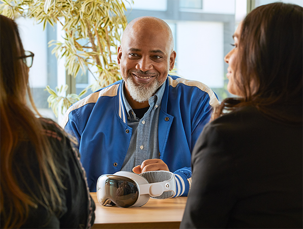 Três colegas em uma reunião, com um Apple Vision Pro sobre a mesa.