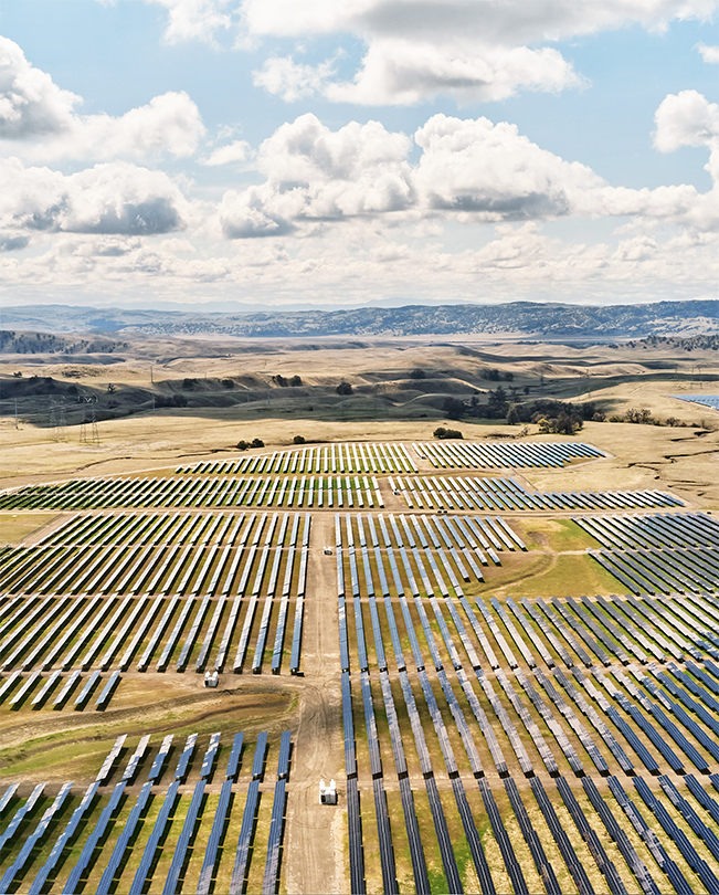 Aerial view of an expansive plain dotted with energy-producing solar panels.