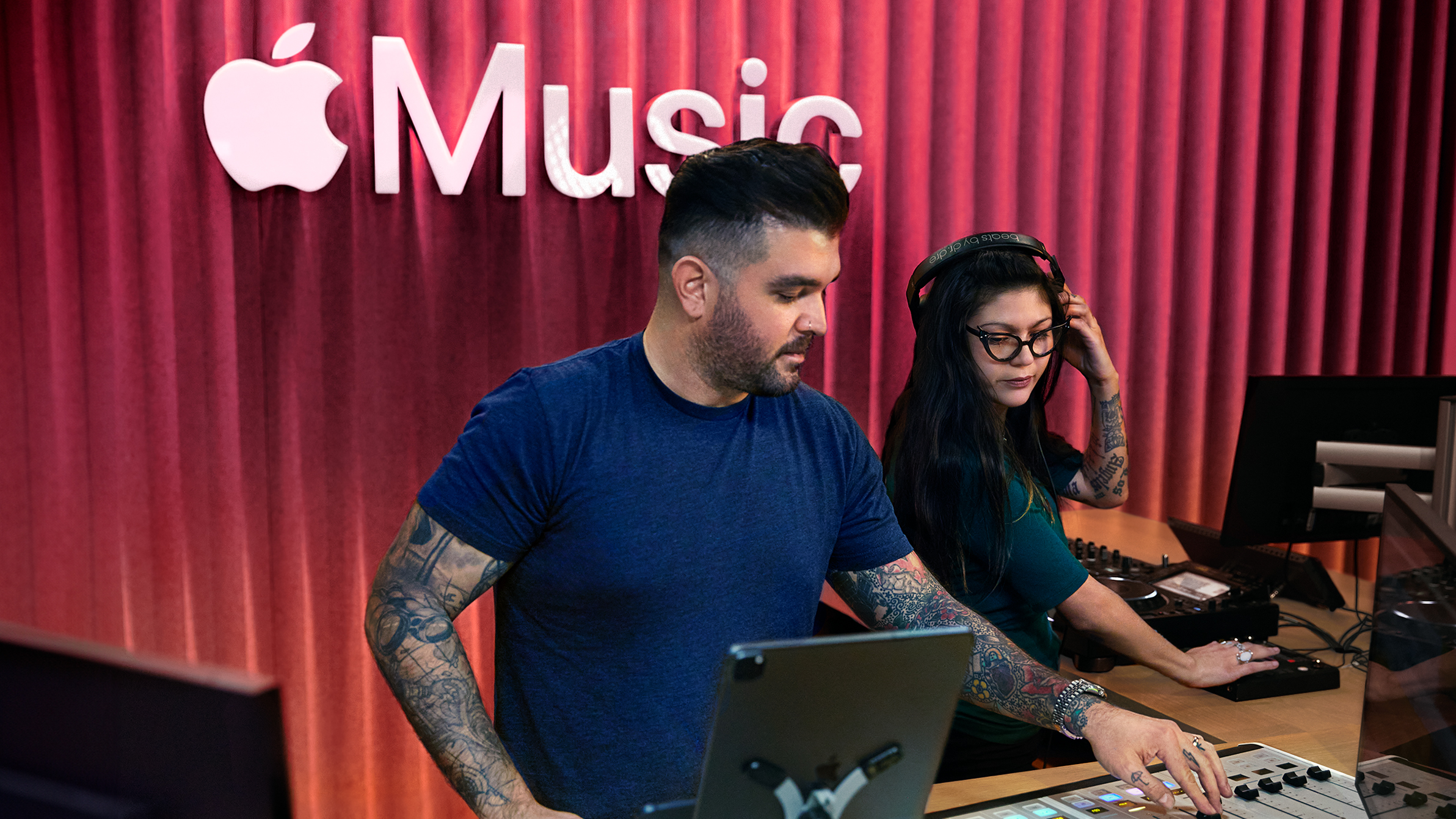 Dois colegas da Apple usam uma mesa de mixagem em um estúdio do Apple Music.