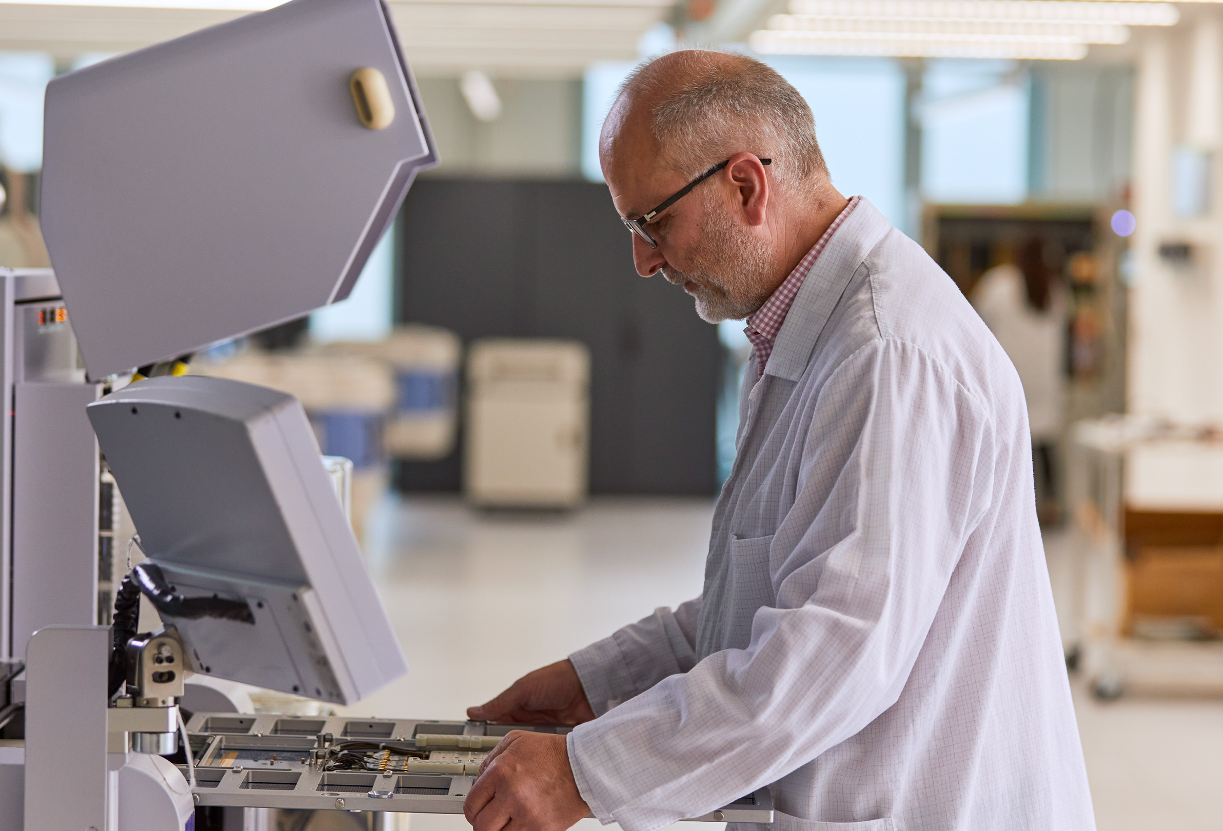 Un empleado de Apple viste una bata blanca de laboratorio y trabaja con un equipo de ingeniería. 