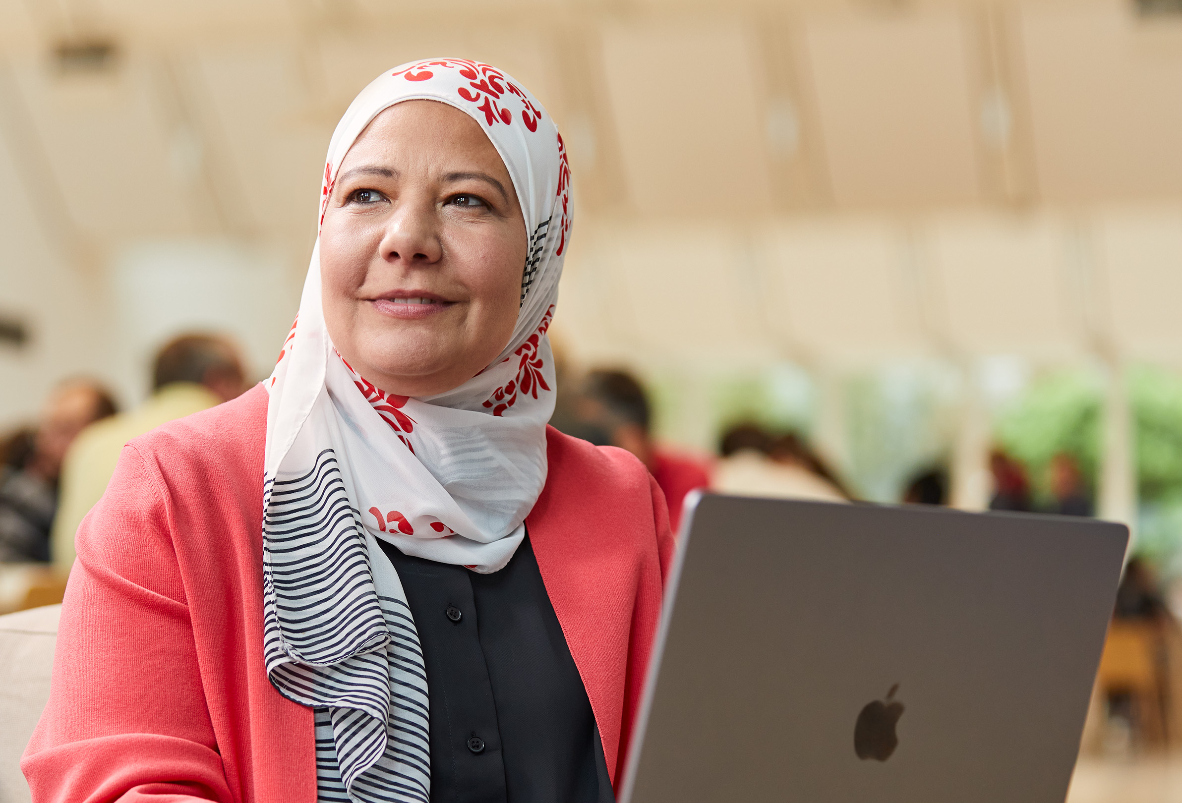 Eine Apple Mitarbeiterin arbeitet im Sitzen an einem MacBook und sieht nach links.