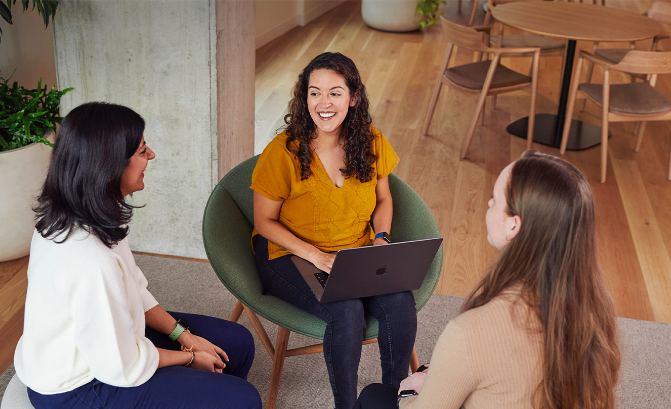 Trois employées Apple discutent assises à une table.