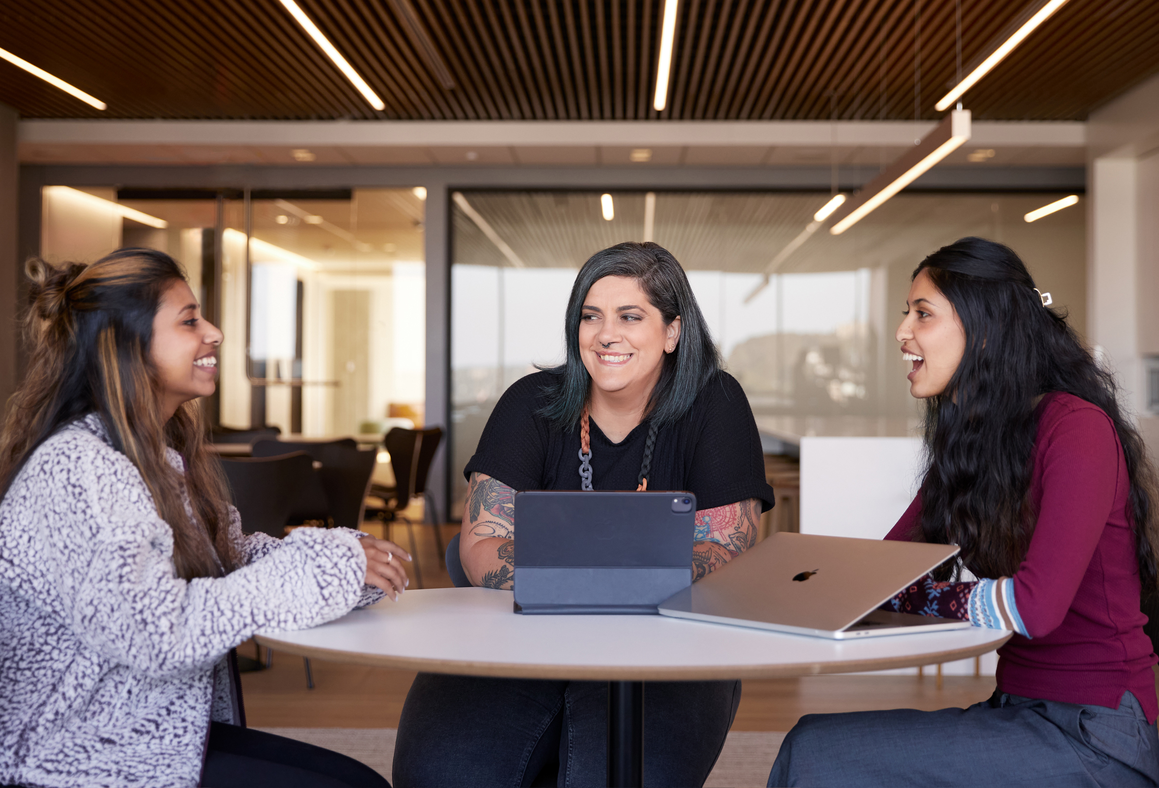 Trois employées Apple discutent assises à une table.