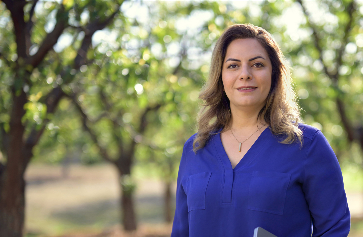 Portret stojącej Desireh, która trzyma MacBooka i uśmiecha się do aparatu