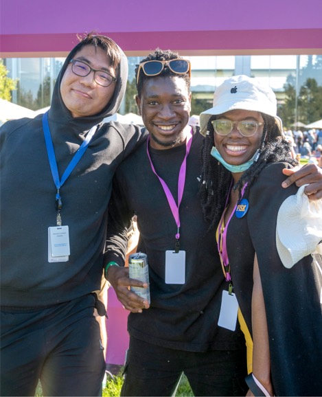 Tres becarios de Apple de pie abrazados y sonriendo a la cámara.