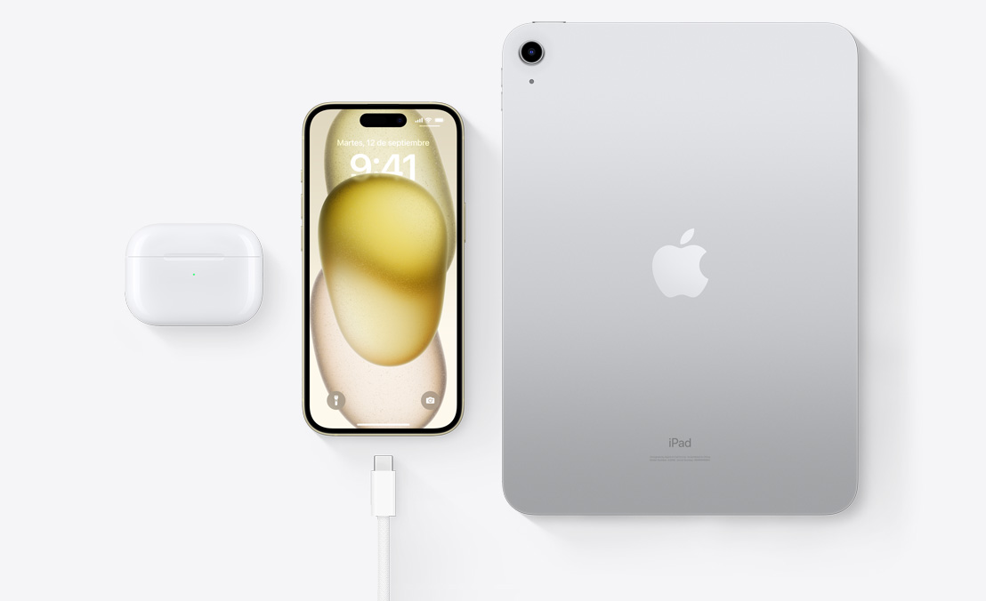 Vista aérea de unos AirPods Pro, un iPhone 15 y un iPad con conector USB-C que demuestra cómo los tres dispositivos pueden cargarse con el mismo cable USB-C.