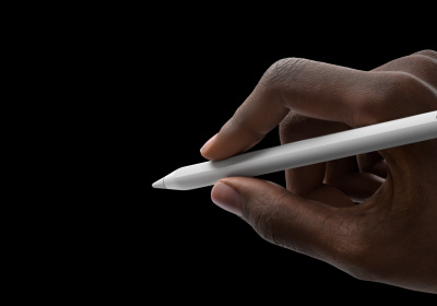 Tangan seorang pengguna yang memegang Apple Pencil Pro dalam posisi menulis. Ujungnya menunjuk ke antarmuka yang memperlihatkan palet alat baru.