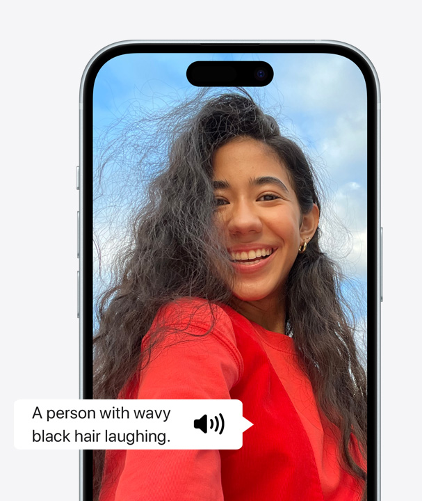 A picture of an iPhone using VoiceOver to describe the details of a person on screen laughing with wavy hair.