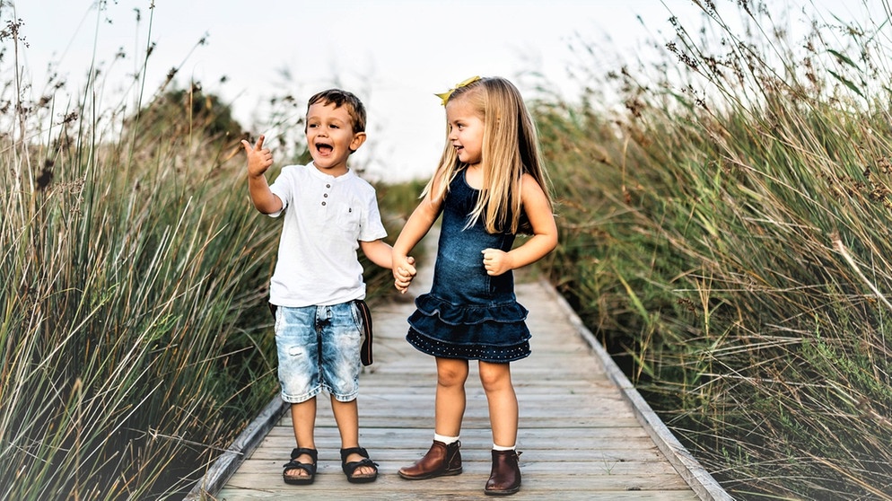 Kinder sprechen miteinander auf einem Steg | Bild: picture alliance / Westend61 | Josep Rovirosa