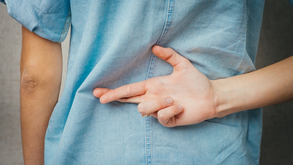 Frau überkreuzt die Finger hinter dem Rücken. Lügen Menschen wirklich 200 Mal am Tag? Im Schnitt wohl eher zweimal am Tag - und auch mit ganz unterschiedlichen Arten von Lügen: Es gibt Weiße und Schwarze Lügen. Wir erklären die verschiedenen Gründe, warum jemand lügt, ob man Lügner an der Körpersprache erkennen kann - und wann Notlügen helfen können. | Bild: colourbox.com