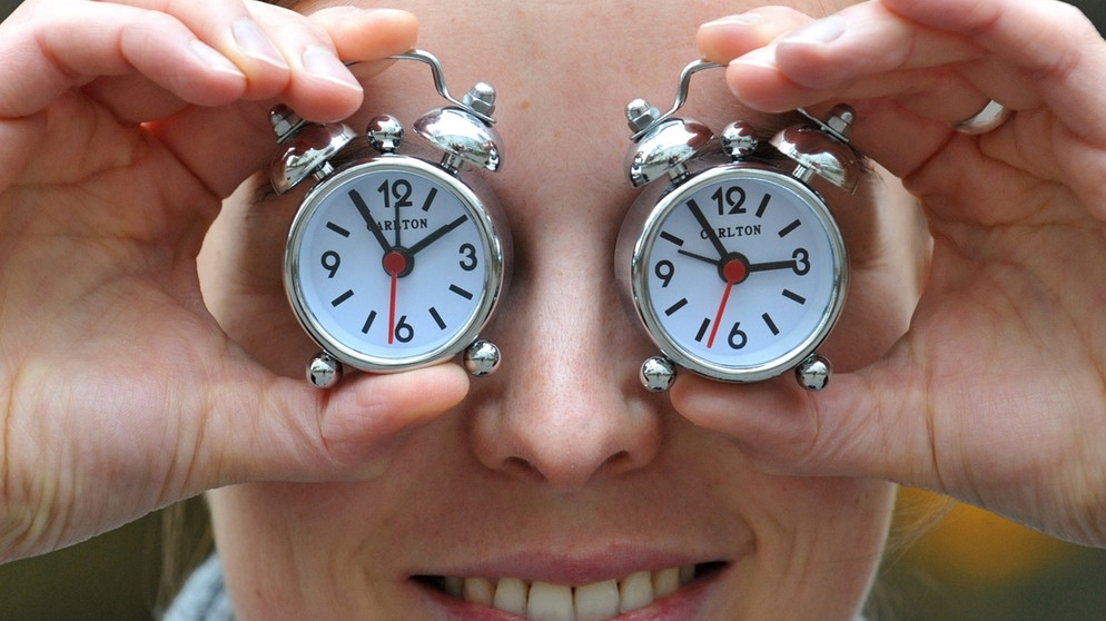 Wer hat an der Uhr gedreht? Bei der Zeitumstellung im Frühjahr und im Herbst kommen viele mit der Uhrzeit durcheinander.  Im Bild: Frau mit Uhren auf den Augen | Bild: picture-alliance/dpa